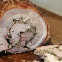 Sliced porchetta on a wooden chopping board.