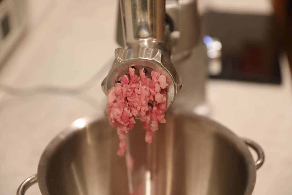 Close up of pork mince coming out of a mincer into a bowl