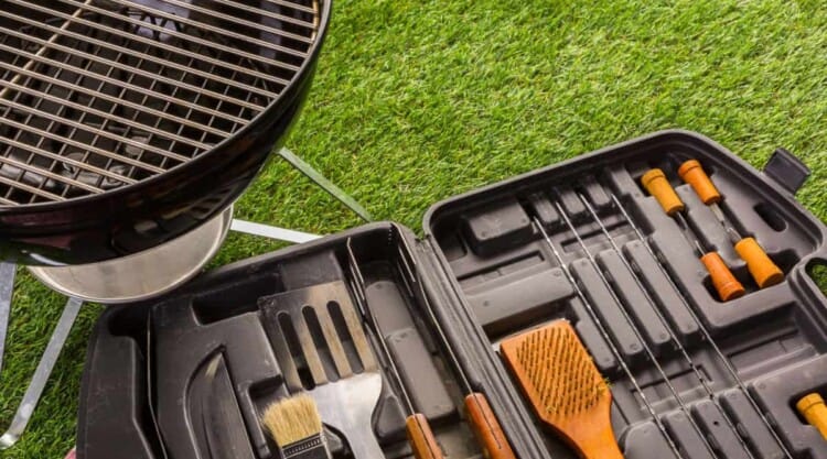 A bbq accessory set next to a kettle grill on grass