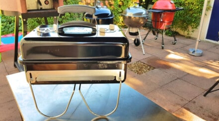 Weber go anywhere tabletop grill on a stainless steel table.