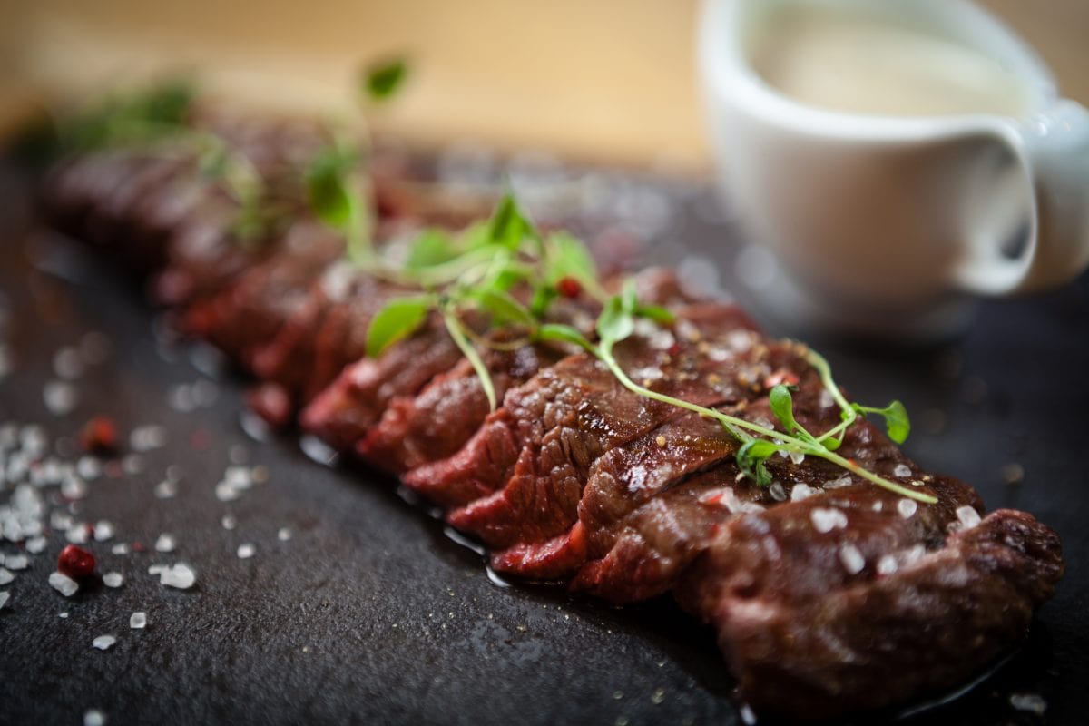 Grilled rare flank steak with salad leaves and a white sauce