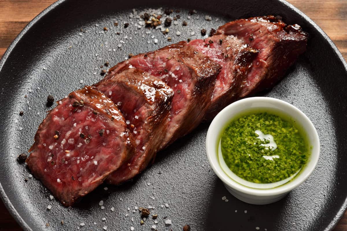 Sliced, grille skit with chimichurri in a white rame.