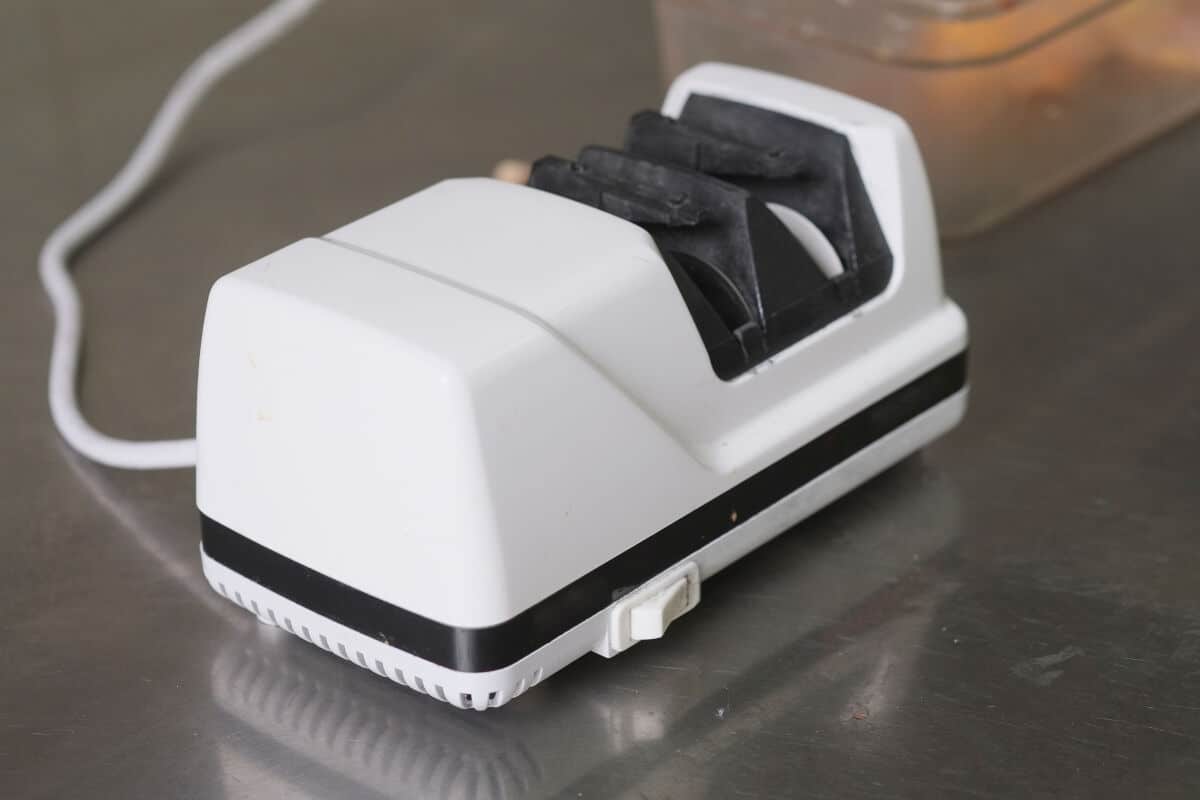 A white electric knife sharpener on a metal table