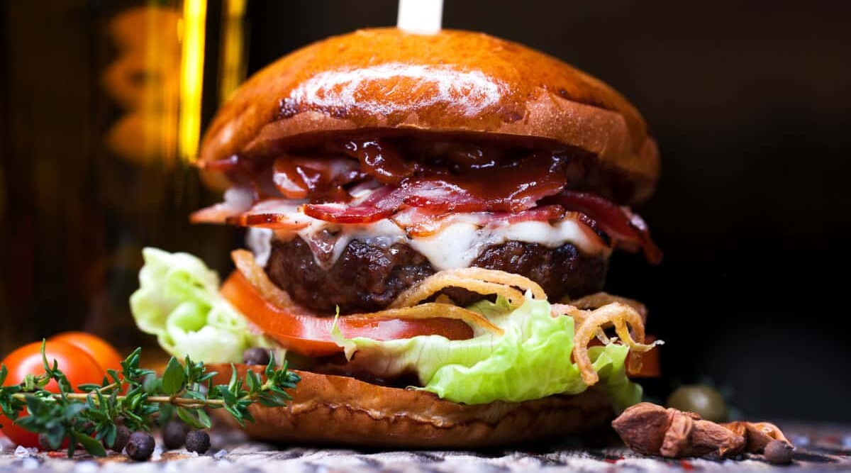 Close up of a burger with tomato and lettuce.