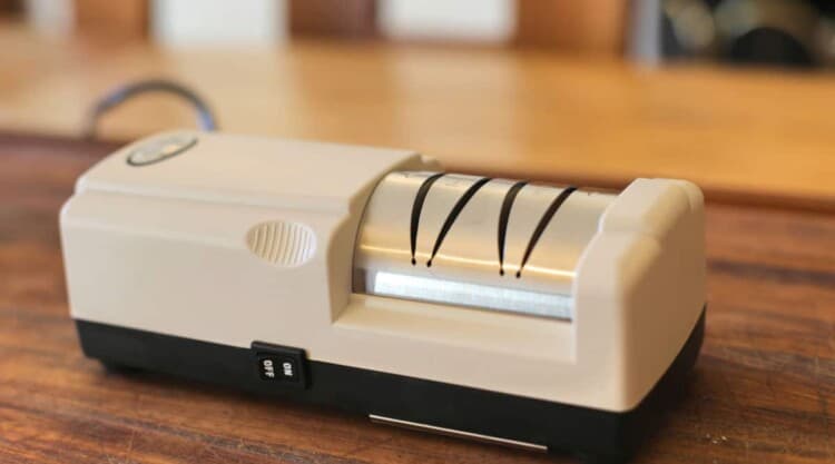 Close up of an I o shen electric knife sharpener on a wooden chopping board.