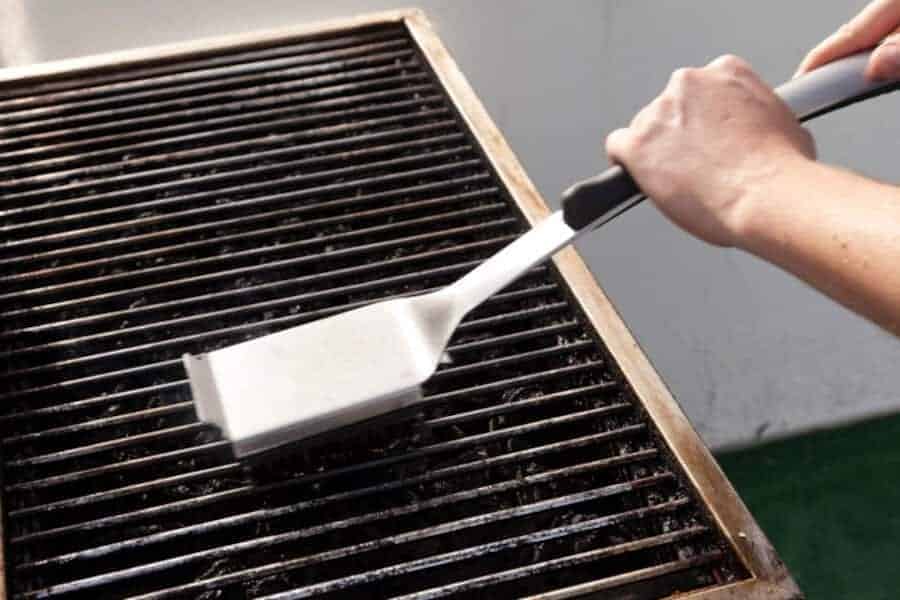 close up of grill grates being scrubbed with a br.