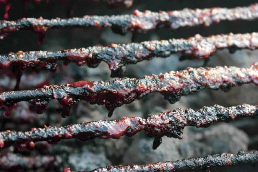 Close up of old food and BBQ sauce on grill gra.