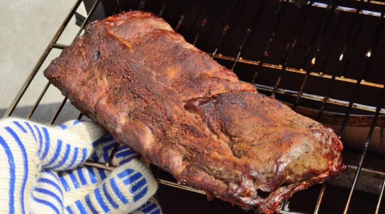 Rack of ribs being removed from an electric smoker.