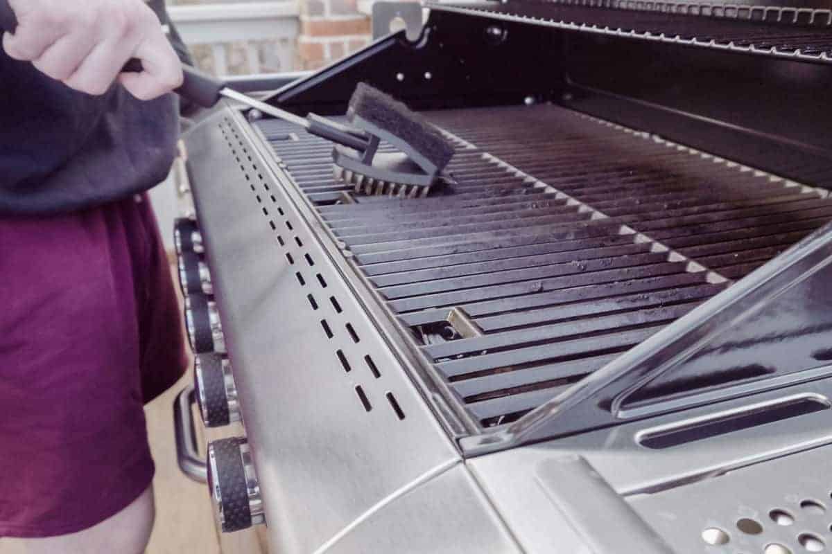 A gas grill being cleaned with a reversible grill br.