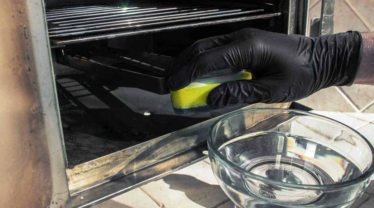 A gloved hand cleaning the inside an electric smoker.