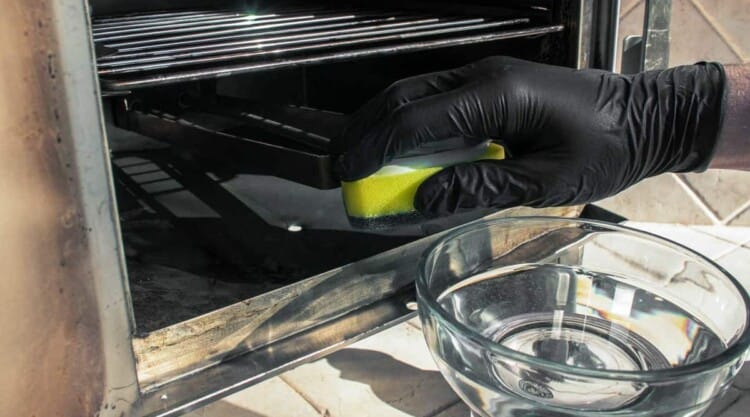 A gloved hand cleaning the inside an electric smoker