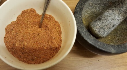 Dry rub in a white bowl next to a pestle and mortar