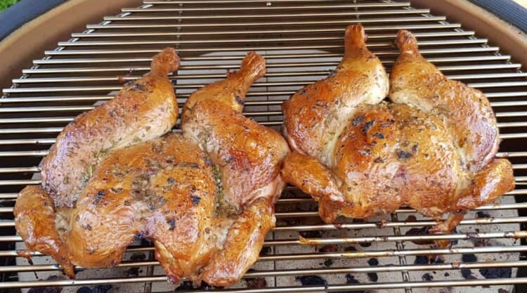 Two spatchcock chicken on a kamado grill.