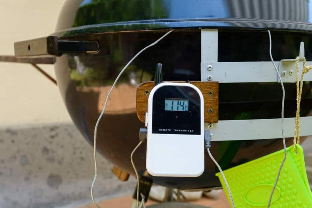 A white dual probe smoker thermometer stuck to the leg of a BBQ