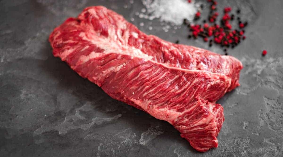 Hanger steak on a slate chopping board with some pink pepper.