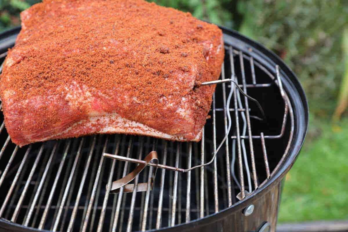 A smoker thermometer with a probe in a pork butt on a WSM