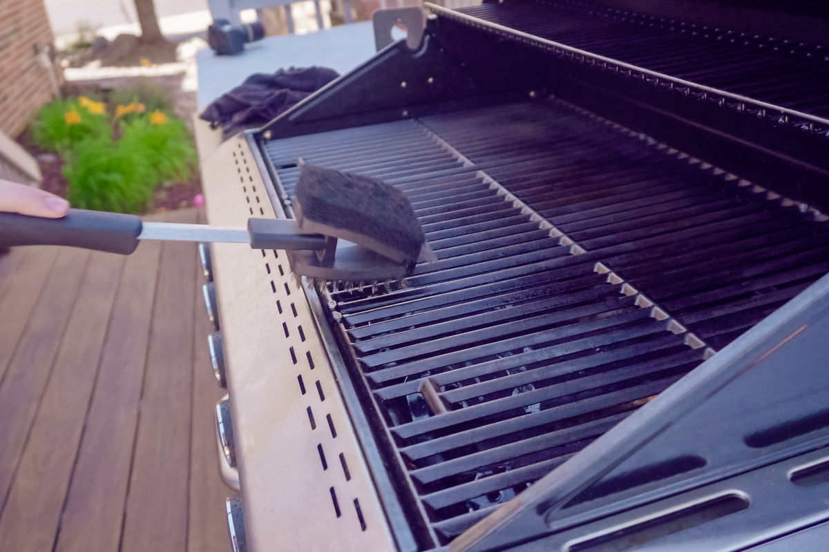 Grill grates being cleaned with a 2-sided brush and scou.