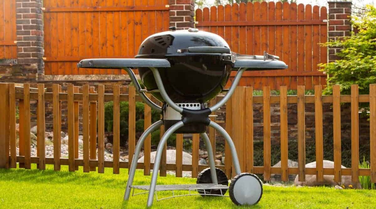 A clean charcoal grill on a grass lawn.