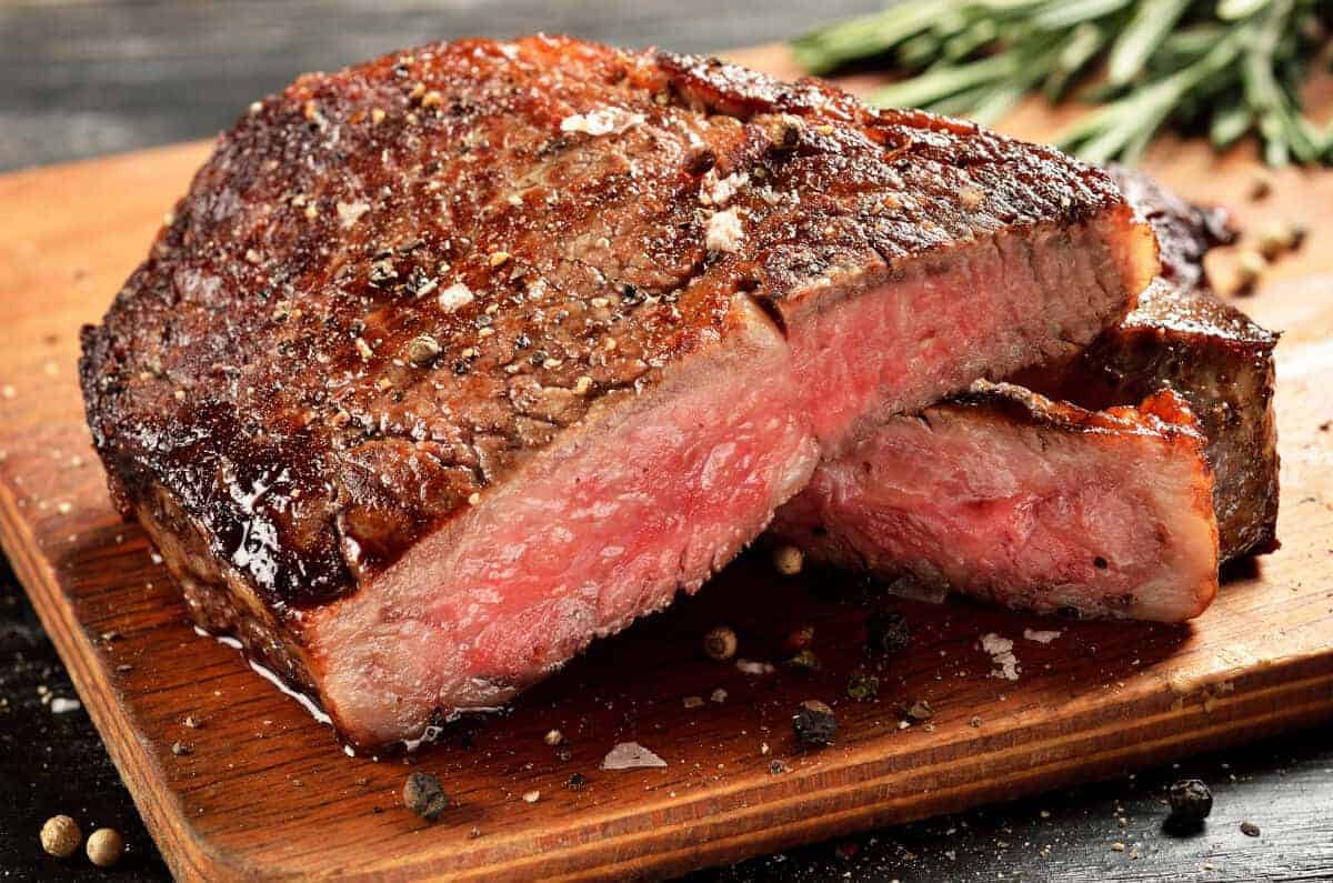 A perfectly medium-rare cooked ribeye steak sliced in half