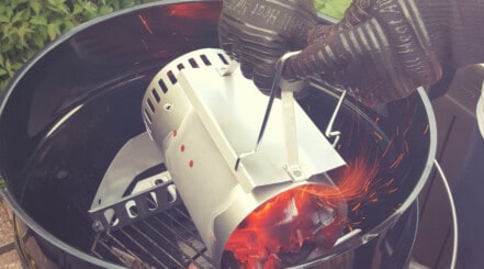 Using a charcoal chimney starter to fill a grill with coals.