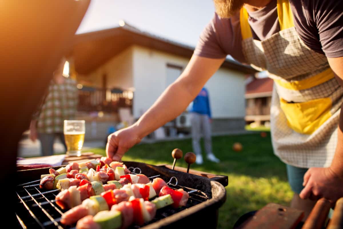 A man grilling kebabs on an open gr.