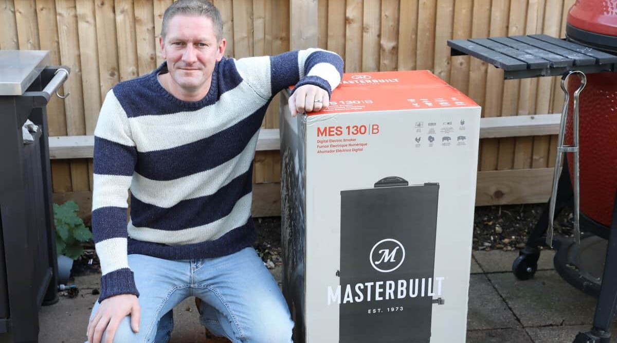 Mark Jenner leaning on a Masterbuilt 30 electric smoker, brand-new still in its box.