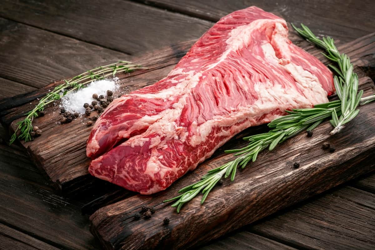 raw hanger steak on a cutting board with rosem.