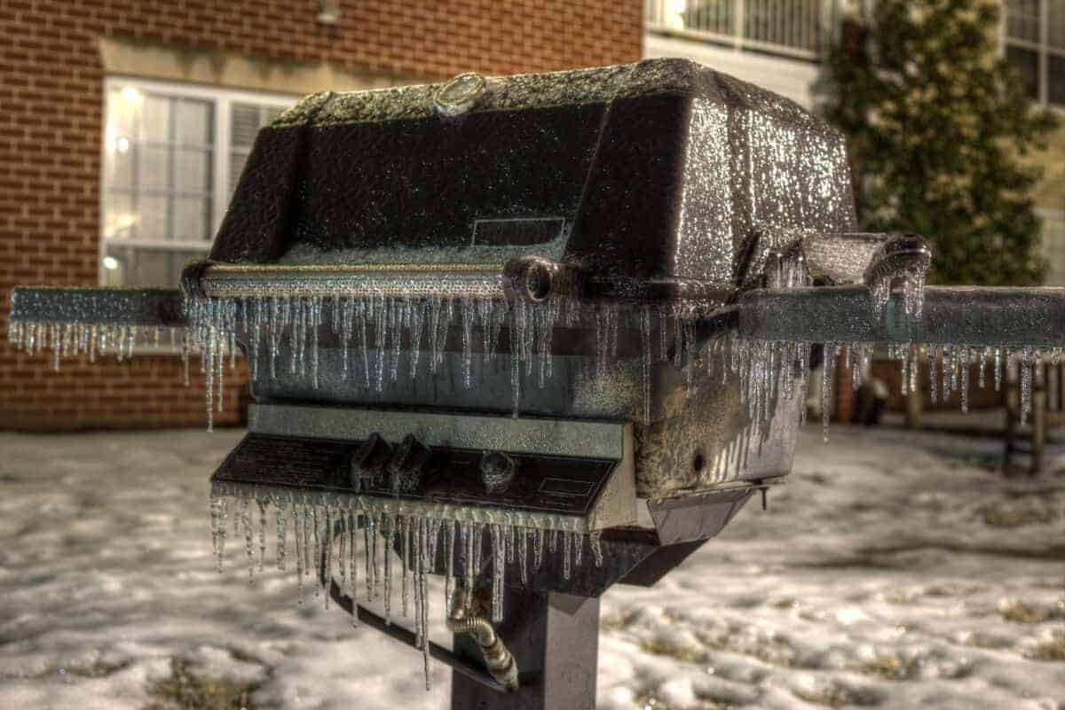 An outside grill covered in icicles in win.