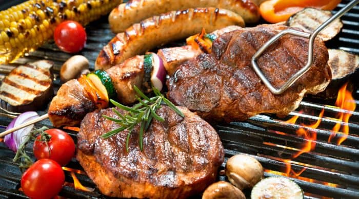 An assortment of meats and vegetables on a hot grill.