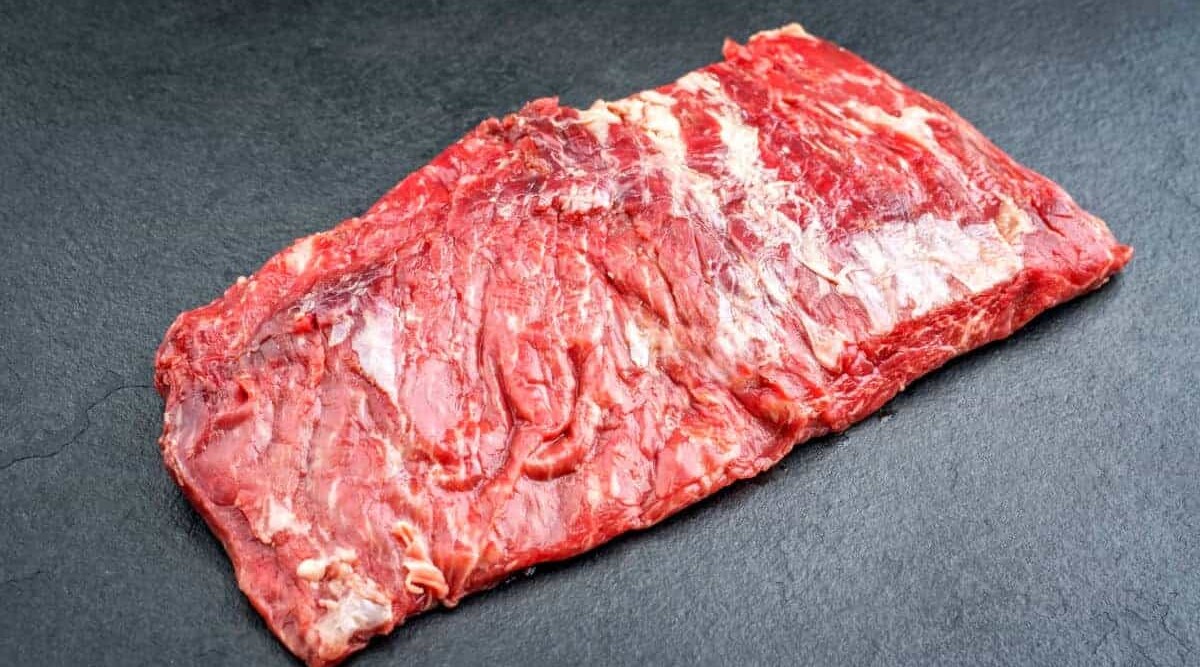Raw bavette steak on what looks like a slate background.