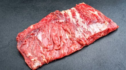 Raw bavette steak on what looks like a slate background.