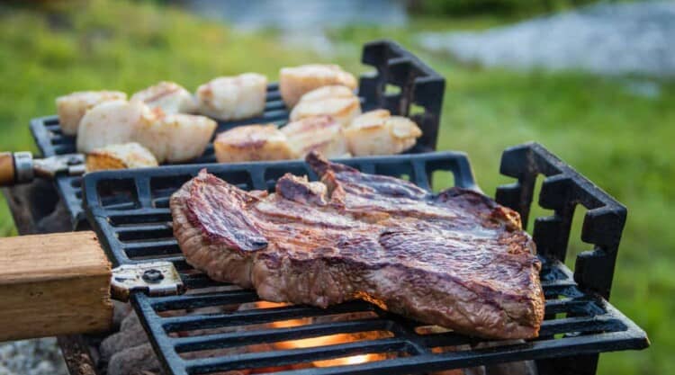 An hibachi grill outdoors, grilling steak and scallops.