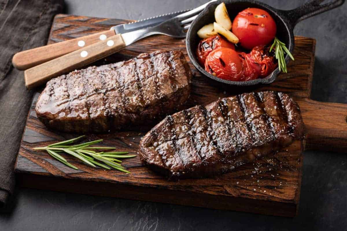 Two cooked top blade steaks with tomato.