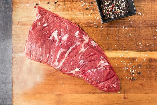 crowd cow bavette steak photographed from above, on a cutting board with a pot of peppercorns