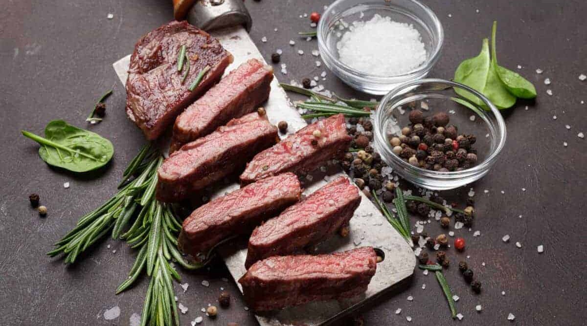 Denver steak grilled, sliced and placed on a large meat cleaver.