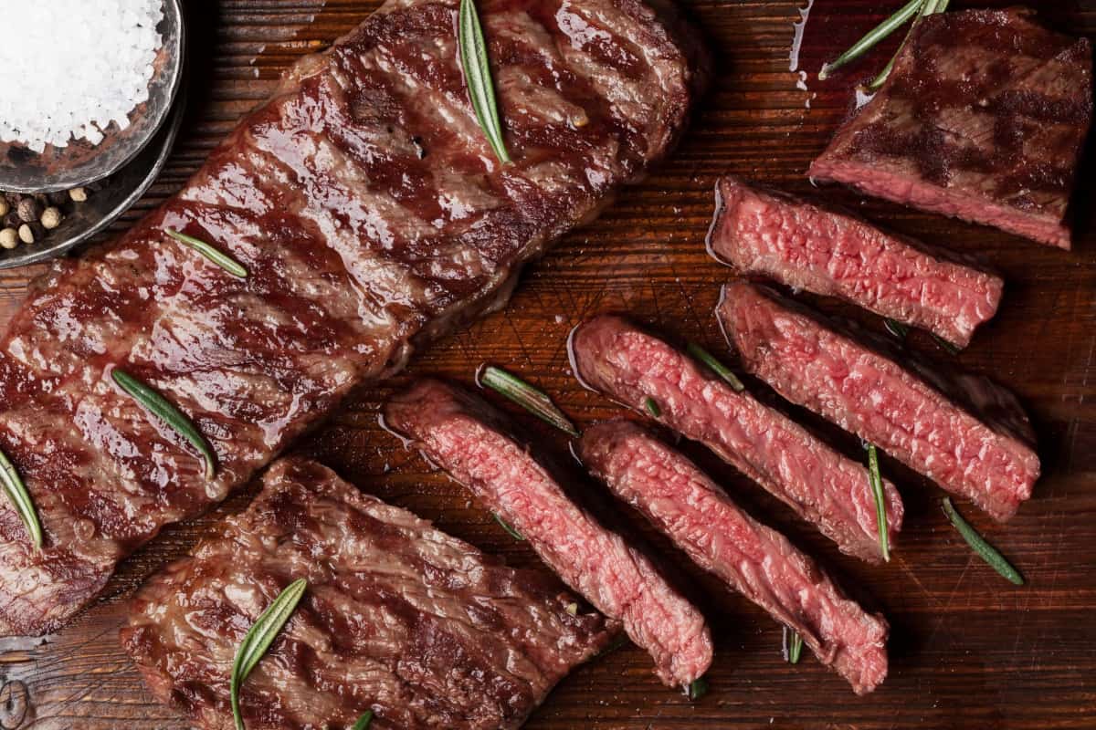 Grilled and sliced top blade steaks with a pot of sea salt and some rosemary lea.