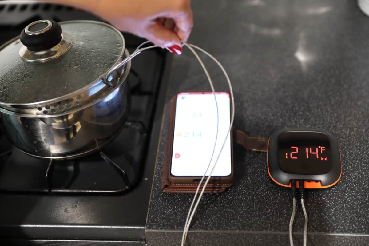 Inkbird ibt-4xs next to a pan of boiling water, being used to measure its temperature.