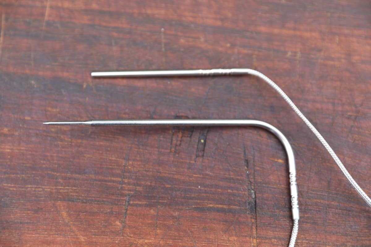 Two Inkbird temperature probes on a wooden cutting board.