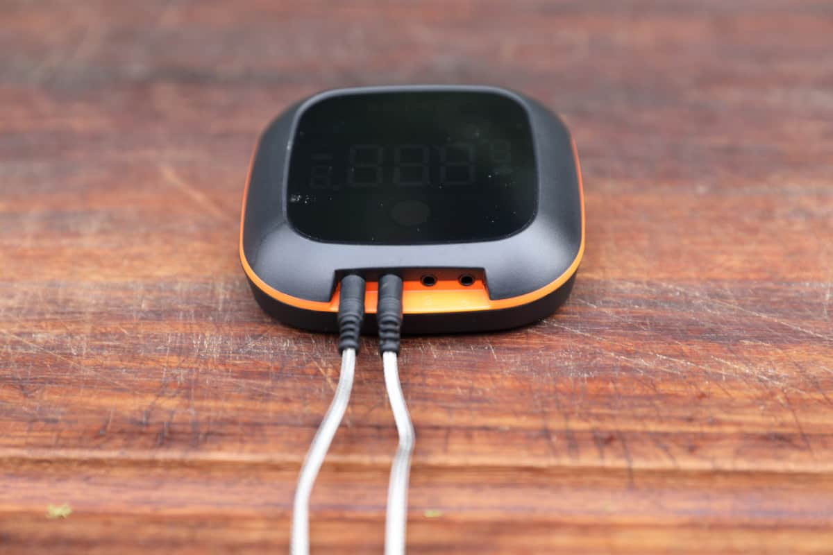 Inkbird thermometer controller with two plugs inserted, sat on a wooden cutting board