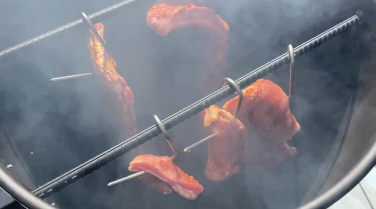 A few racks of ribs smoking inside a pit barrel cooker.