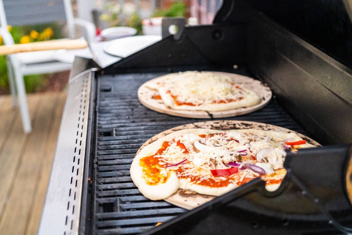 Two pizza stones with pizza on them in a gr.