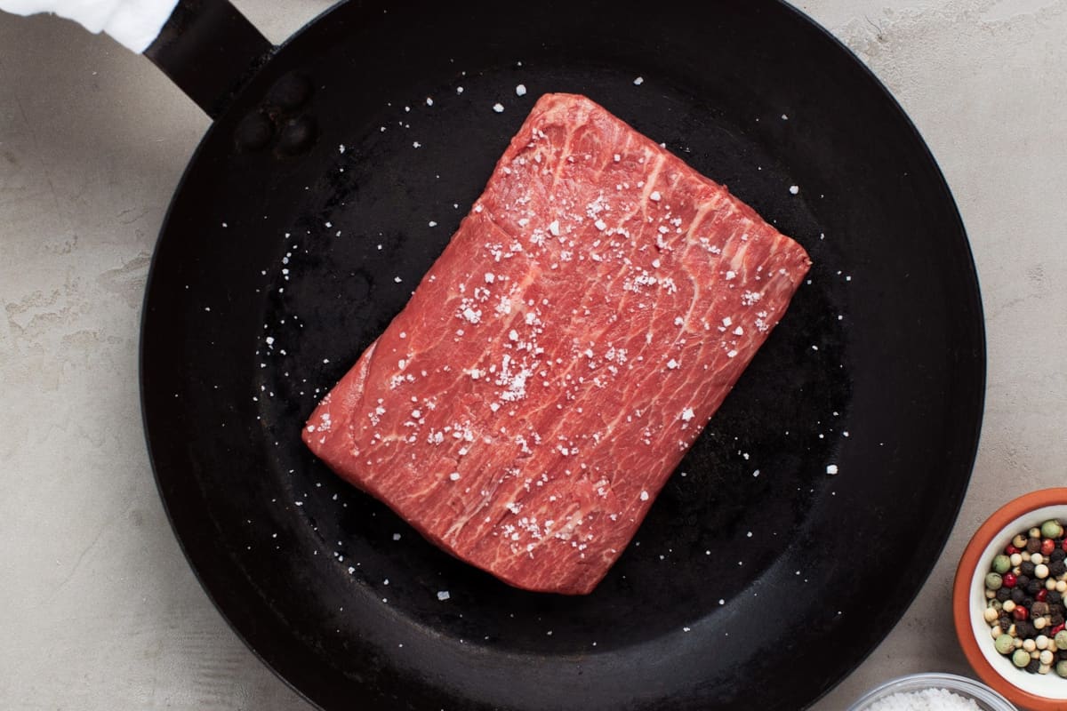A flat iron steak from Porter Road, in a cast iron pan, sprinkled with salt
