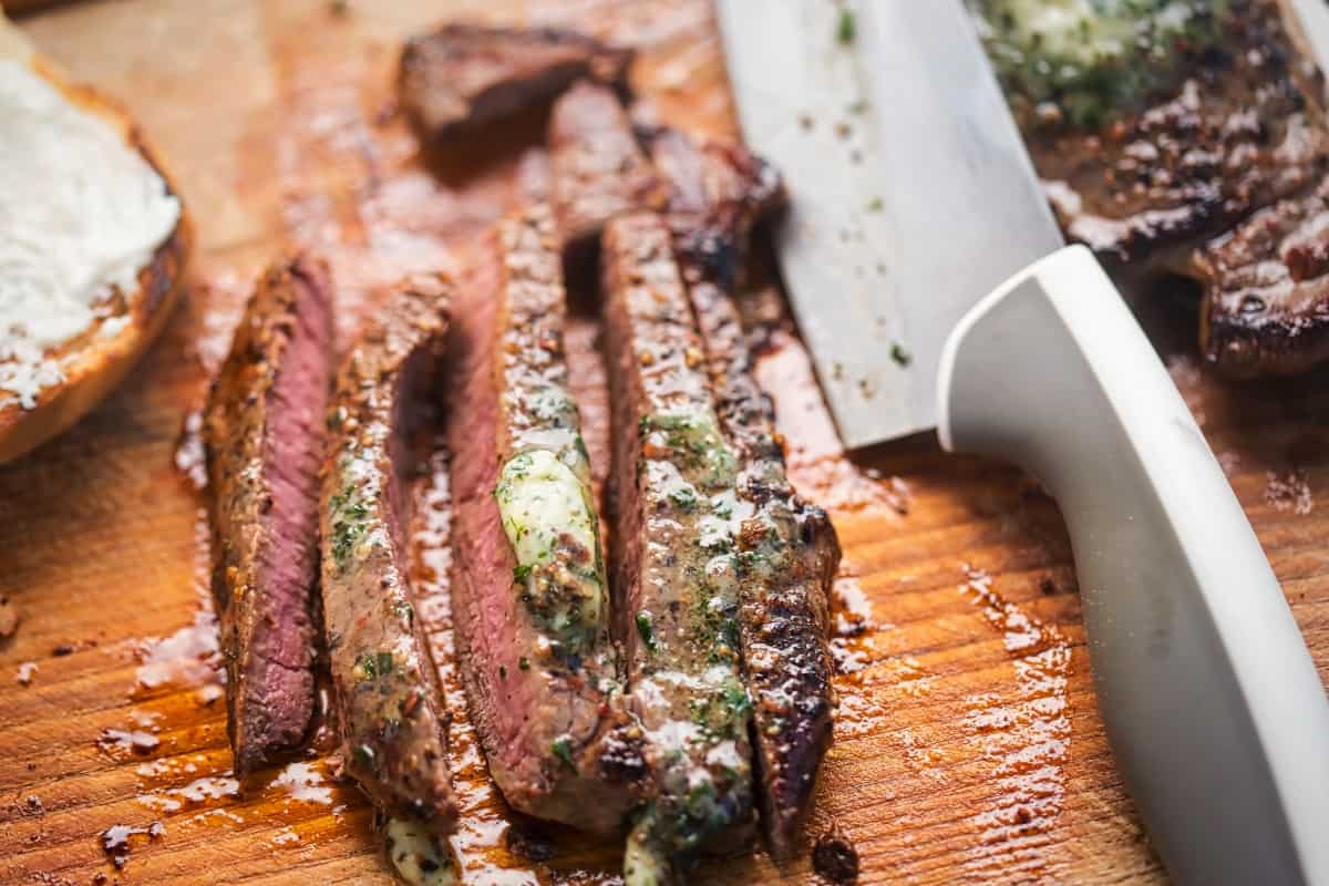 Sliced ranch steak with melted herb butter on the cr.
