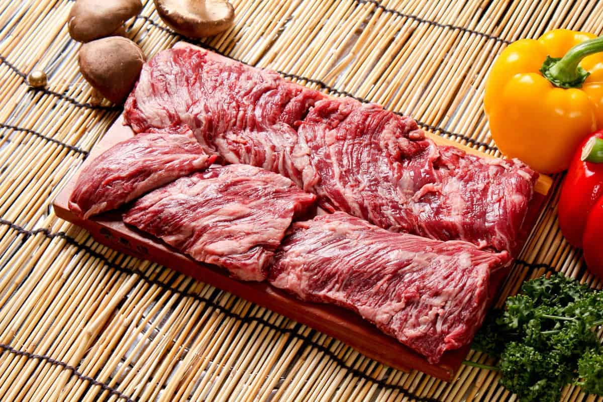 Two uncooked skirt steaks on a wooden cutting board