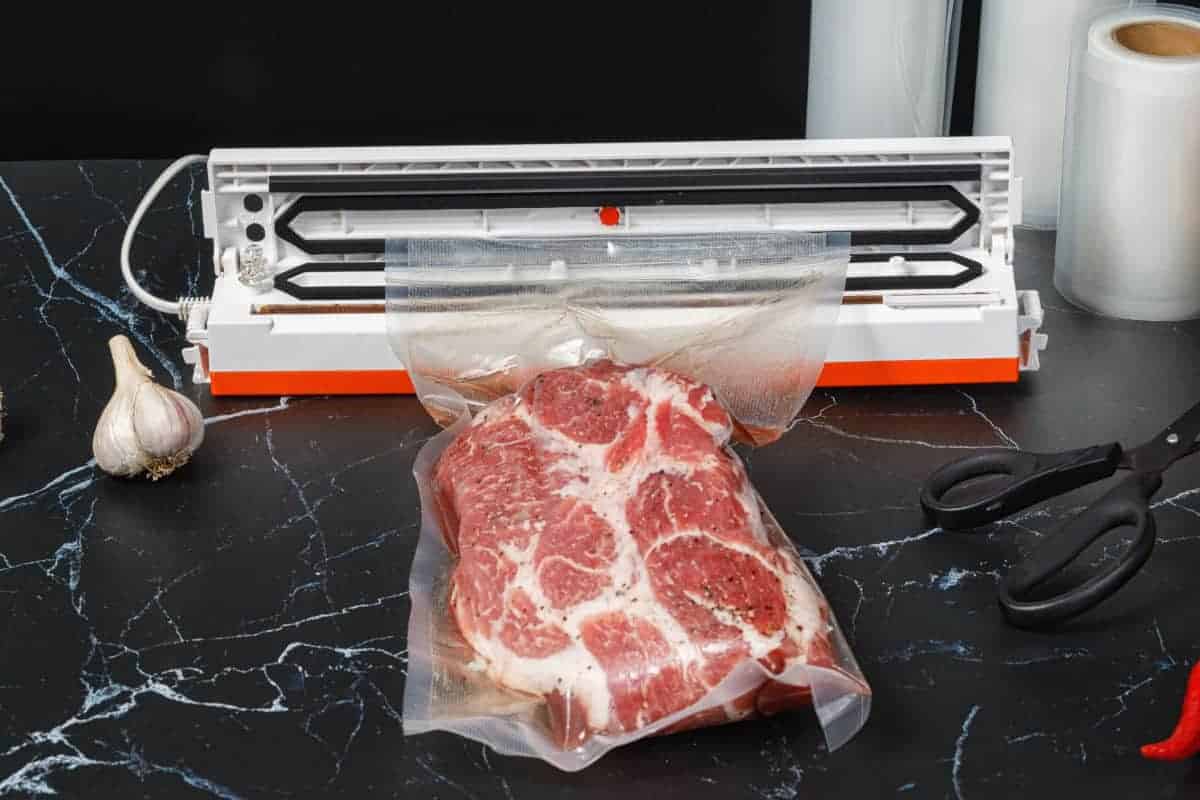 A vacuum sealer in use to seal meat in plastic