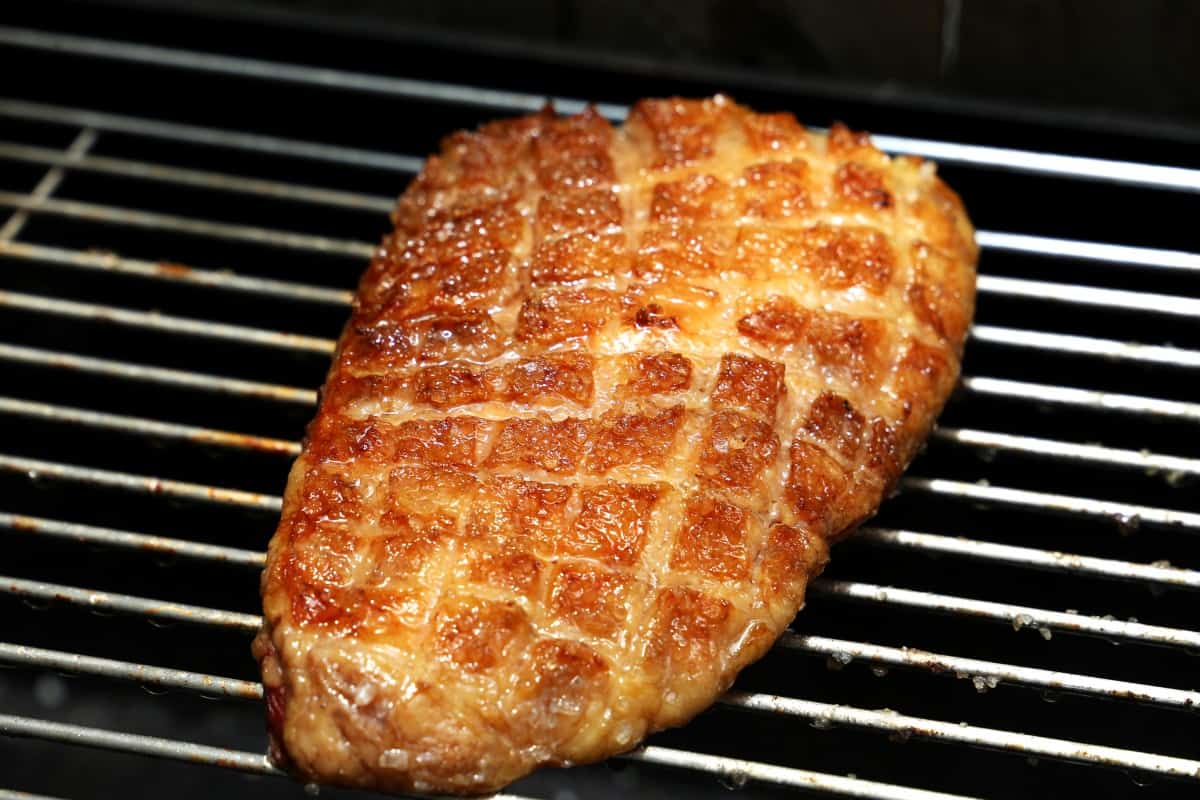 A whole roasted picanha with criss cross scores on the fat .