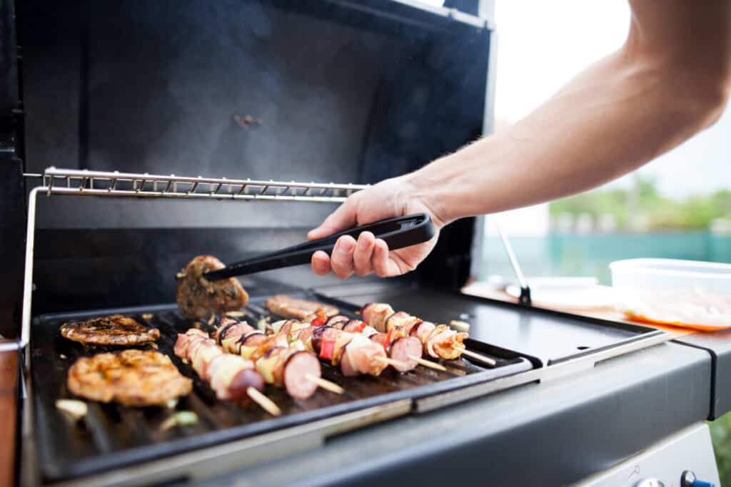Man turning food on an outdoor BBQ gr.