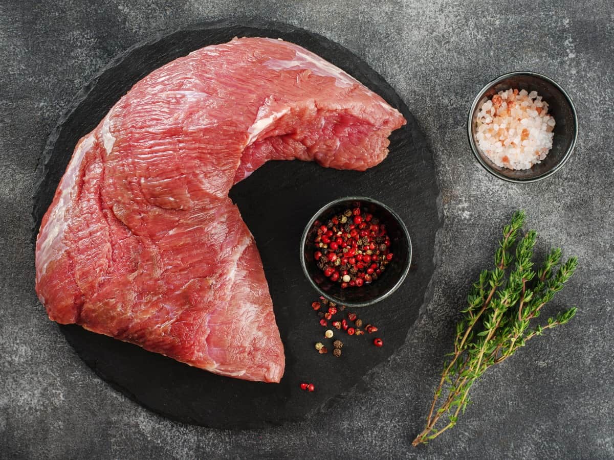 生の牛肉のトライチップを黒のプレートに入れ、乾いた摩擦の鍋を入れた