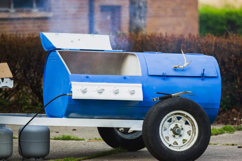 A big, blue, trailer pulled gas and charcoal combo grill