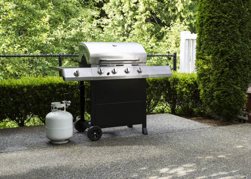 A propane gas grill with cylinder beside it